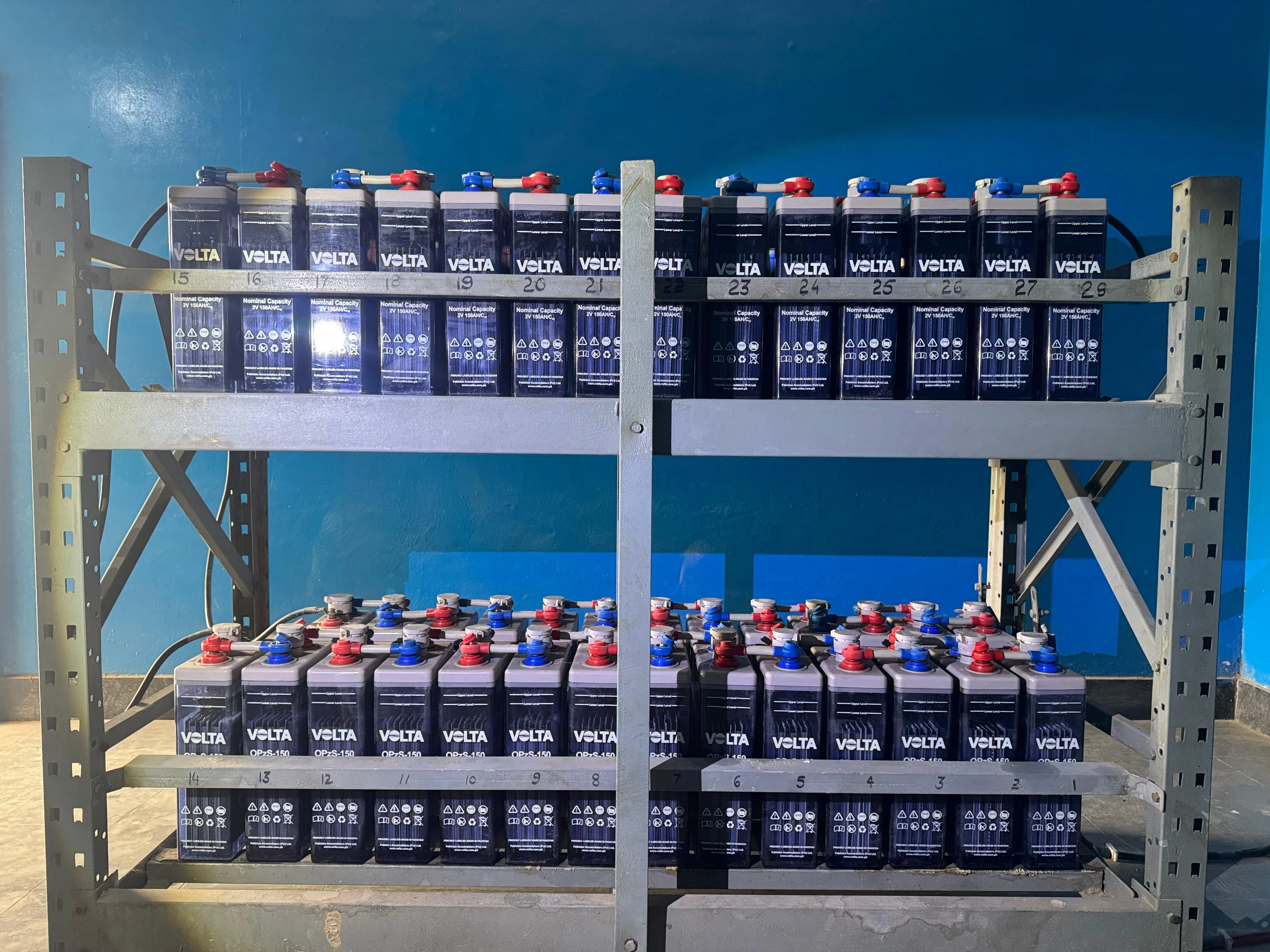 Two-tier substation battery bank with connected lead-acid cells on a steel rack.