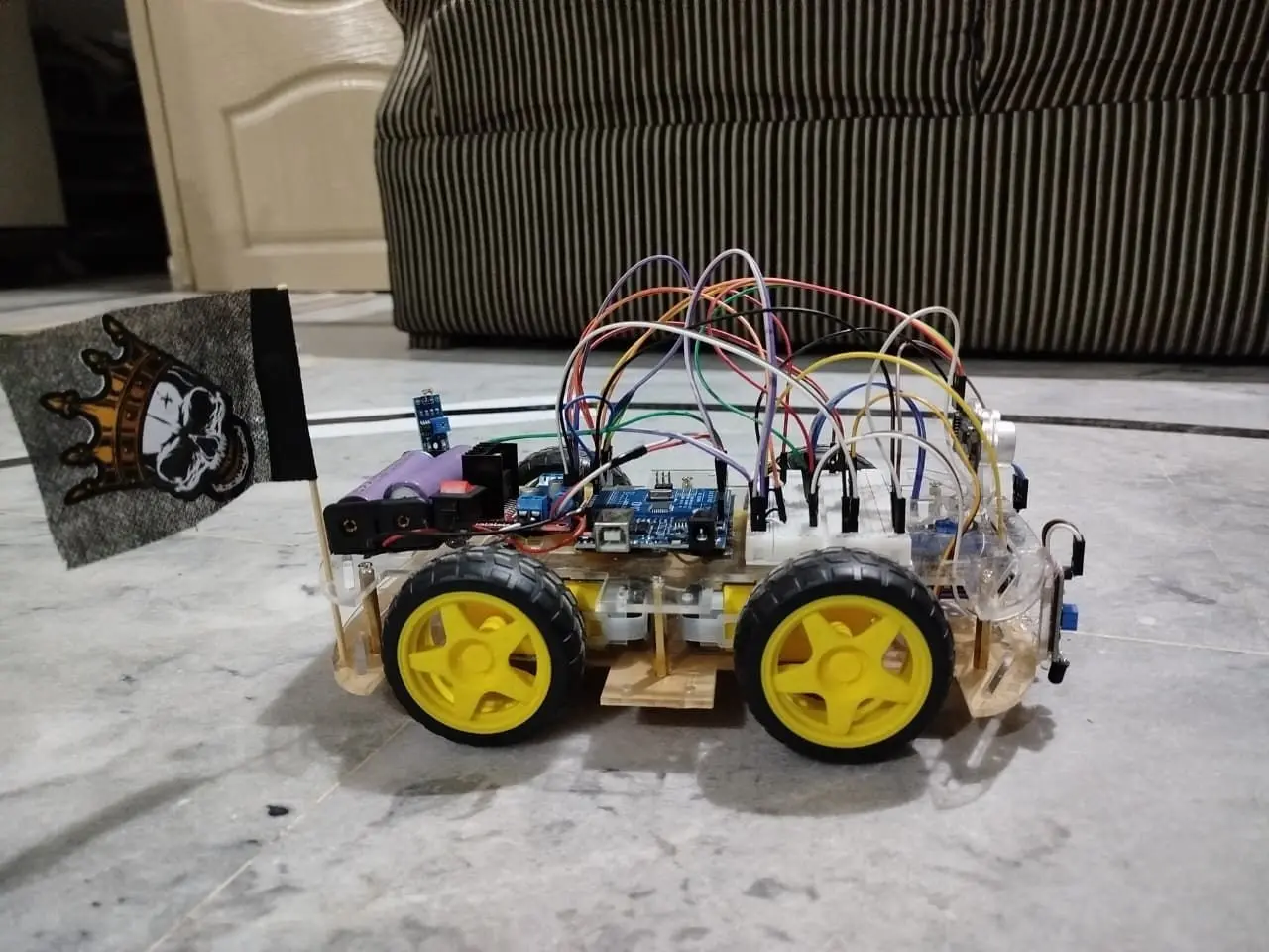 Arduino-based four-wheel robot with breadboard wiring, battery cells and yellow wheels.