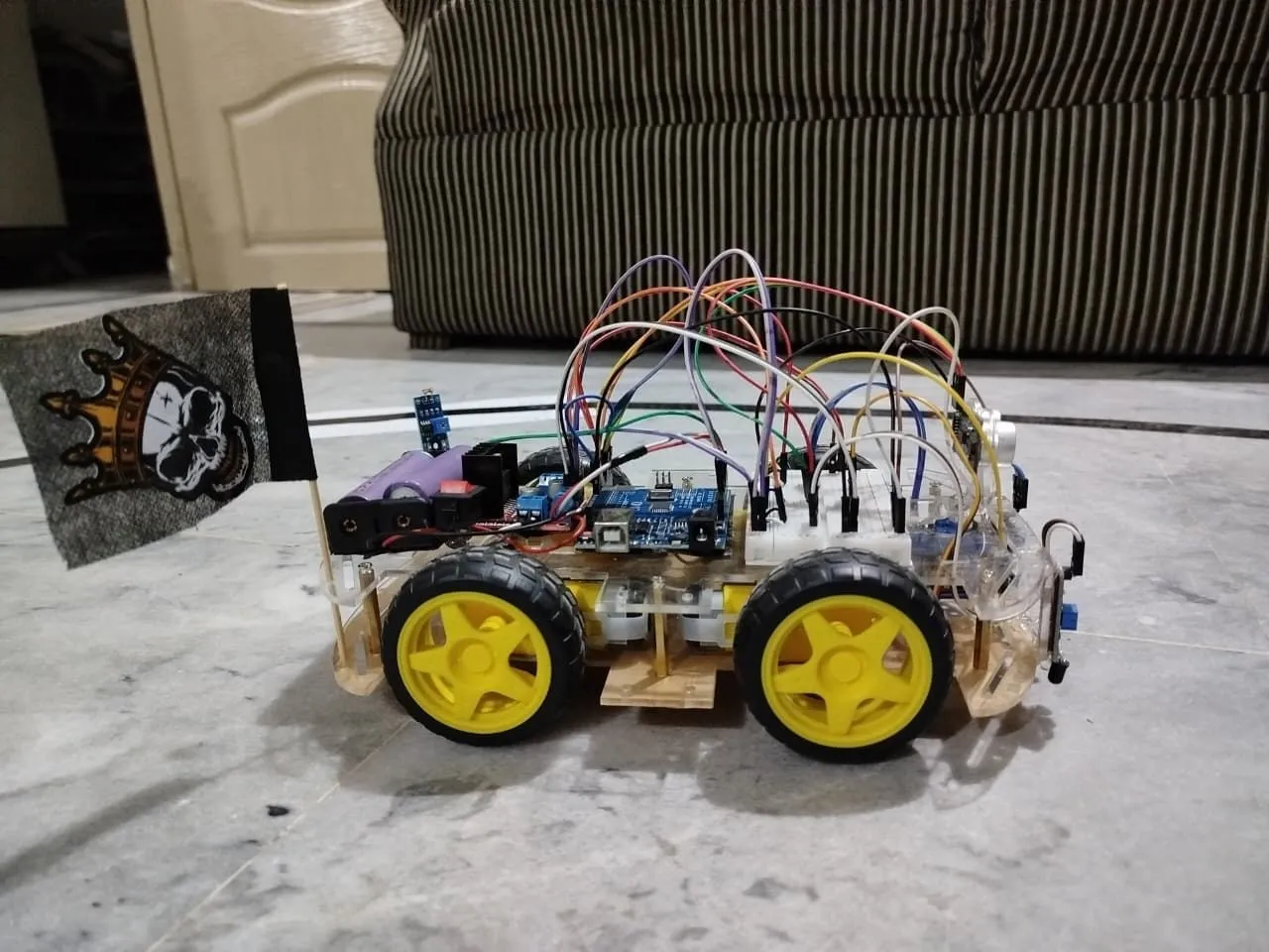 Arduino-based four-wheel robot with breadboard wiring, battery cells and yellow wheels.